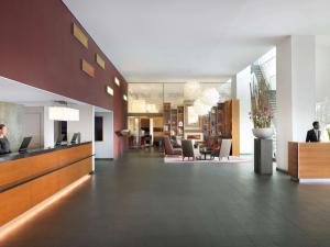un hall avec des personnes assises à un bureau dans un bâtiment dans l'établissement Mövenpick Hotel Amsterdam City Centre, à Amsterdam