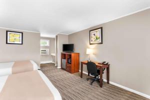 a hotel room with a bed and a desk with a computer at Rodeway Inn Gorham Riverside in Gorham