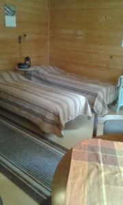 1 dormitorio con 2 camas en una pared de madera en Pihlajamäen Lomamökit en Vanhakylä
