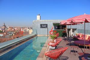 a swimming pool with chairs and tables on a building at Pestana Collection Plaza Mayor in Madrid