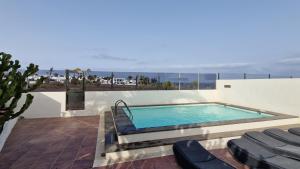 a swimming pool on top of a house with chairs at Bungalow El Mar in Teguise