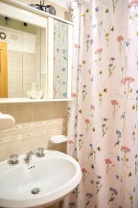 a bathroom with a sink and a shower curtain with flowers at Da Carla in Santa Maria degli Angeli +25 photos