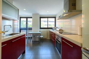 eine Küche mit roten Schränken und einer Spüle in der Unterkunft Moderno Apartamento TEMPORAL Familiar con Terraza SOD1 in Madrid