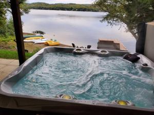 Private beach with SPA on the lake I Plage Sucrée في Saint-Rémi-dʼAmherst: حوض جاكوزي مطل على البحيرة