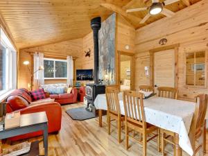 Private beach with SPA on the lake I Plage Sucrée في Saint-Rémi-dʼAmherst: غرفة طعام وغرفة معيشة مع موقد في كابينة خشبية +30 صورة