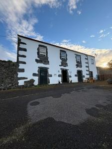 a white building with black windows on the side of it at Casa da Madrinha Graciosa in Trás dos Pomares