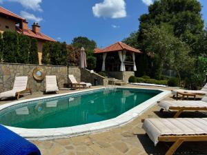 a swimming pool with chairs and a gazebo at Etno selo Milanovic - Nonac in Kuršumlija