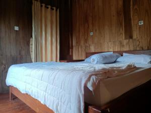 a bedroom with a bed with a wooden wall at Noor Homestay Tetebatu in Tetebatu