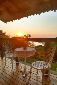 a table and two chairs on a deck with the sunset at Minas Em Marambaia in Rio de Janeiro