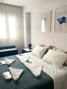 a large bed with white sheets and towels on it at Odysseus Boutique Apartment in Ermioni