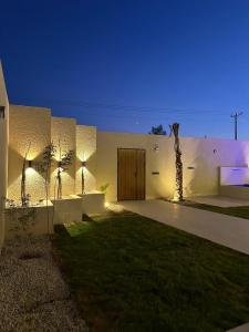 a white building with a door and a palm tree at شاليهات رزانه الفندقية in Ilbaras