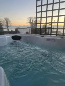 a hot tub with water in it with the sunset in the background at The Barn Springmount Accommodation in Dromara
