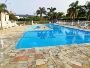a swimming pool with a stone patio and blue water at Casa na Grande Florianopolis in Palhoça
