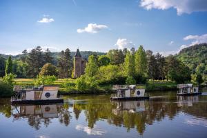 three boats in a river with a church in the background at Schwimmende Ferienwohnung auf der Saar in Merzig
