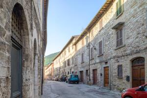 an alley with stone buildings and a blue car parked on a street at Via Mazzini 23A in Gubbio