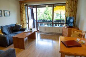 a living room with a couch a table and a tv at Hotel Sonnenhof in Bad Birnbach +7 photos
