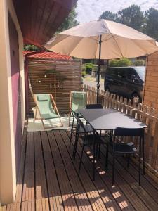 une table, des chaises et un parasol sur une terrasse dans l'établissement appartement T2 proche du golf et de la plage, à Moliets-et-Maa