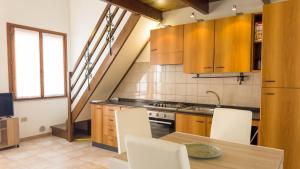 a kitchen with wooden cabinets and a table with chairs at Sardinianworld - Frontemare Apartment-Funtana Meiga in Funtana Meiga
