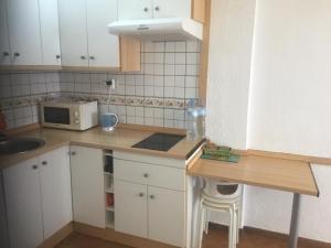 a kitchen with white cabinets and a counter with a microwave at Edificio Comodoro in Los Cristianos