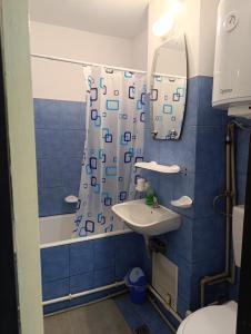 a blue tiled bathroom with a sink and a mirror at Studio in Hunedoara