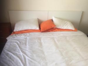 a white bed with two pillows and an orange pillow at Edificio Comodoro in Los Cristianos +13 photos