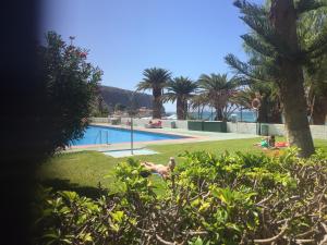 a person laying on the grass near a swimming pool at Edificio Comodoro in Los Cristianos