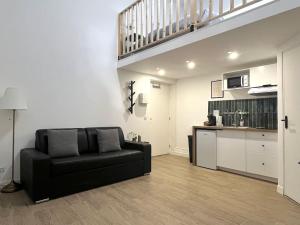 a living room with a black couch and a kitchen at 731 Joli studio mezzanine proche du métro L9 in Bagnolet +6 photos