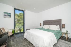 a white bedroom with a large bed and a window at SUPER Camacha - Casa da Eira in Camacha