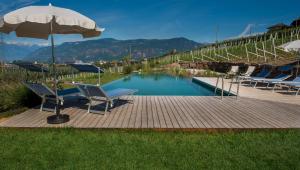 una piscina con 2 sillas y una sombrilla en Lavendelhof, en Appiano sulla Strada del Vino
