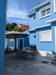een blauw gebouw met een tafel en stoelen en een paraplu bij Villa Gisèle in Le Touquet-Paris-Plage