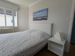 een witte slaapkamer met een bed en een foto aan de muur bij Villa Gisèle in Le Touquet-Paris-Plage