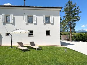 a white house with two chairs and an umbrella at La Villa Suite 2 in Fabriano