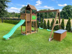 un parque infantil de madera con un tobogán y un columpio en Domy na polanie-Szafirek, en Polanica-Zdrój
