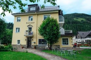 a yellow building with tables and chairs in front of it at Hotel Lindenhof in Bad Gastein