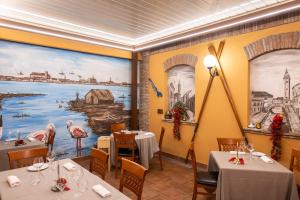 ein Restaurant mit zwei Tischen und einem Gemälde an der Wand in der Unterkunft Locanda La Comacina in Comacchio