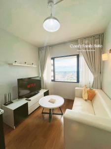 a living room with a white couch and a tv at 2BR Comfy Family Suite Hat Yai in Hat Yai