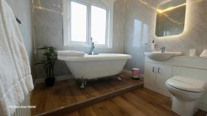 a bathroom with a tub and a sink and a toilet at Bacchus Hotel in Sutton on Sea