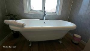 a white bath tub in a bathroom with a window at Bacchus Hotel in Sutton on Sea