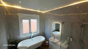 a bathroom with a tub and a sink and a mirror at Bacchus Hotel in Sutton on Sea
