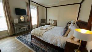 a bedroom with a large bed and a table with a lamp at Bacchus Hotel in Sutton on Sea