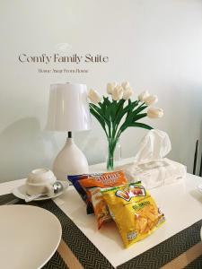 a table with snacks and a vase of flowers and a lamp at 2BR Comfy Family Suite Hat Yai in Hat Yai