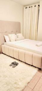 a large white bed with a pair of shoes on a rug at Golden Touch Luxury Superior in Nairobi