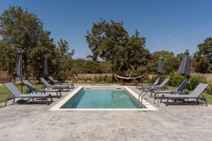 a swimming pool with lounge chairs and umbrellas at Miroy Mountain View Villa in Prinés