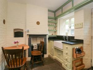 eine Küche mit einem Tisch und einem Kamin in der Unterkunft Teacher's Cottage in Presteigne
