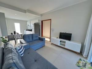 a living room with a blue couch and a tv at Canoa Quebrada, CE in Aracati