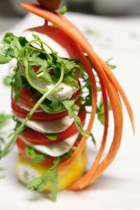 a sandwich with tomatoes and onions on a plate at Hotel Villa Margherita in Quercianella