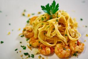 a plate of pasta with shrimp on a white plate at Hotel Villa Margherita in Quercianella