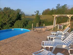 a group of white chairs sitting next to a pool at Casacocco' - Agri Host in San Ginesio