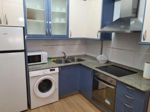a kitchen with blue cabinets and a washing machine at Sol in Cangas de Morrazo