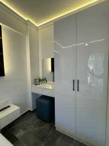 a white kitchen with a sink and a white cabinet at Nōya Suites SR in Sarandë +50 photos